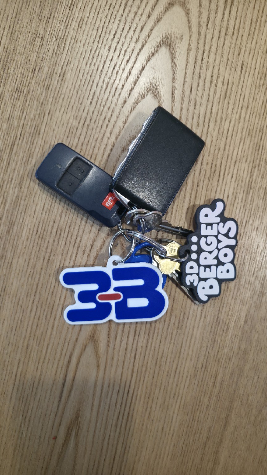 Our printed 3B and Berger Boys keyrings on a set of keys, photographed on a timber table.