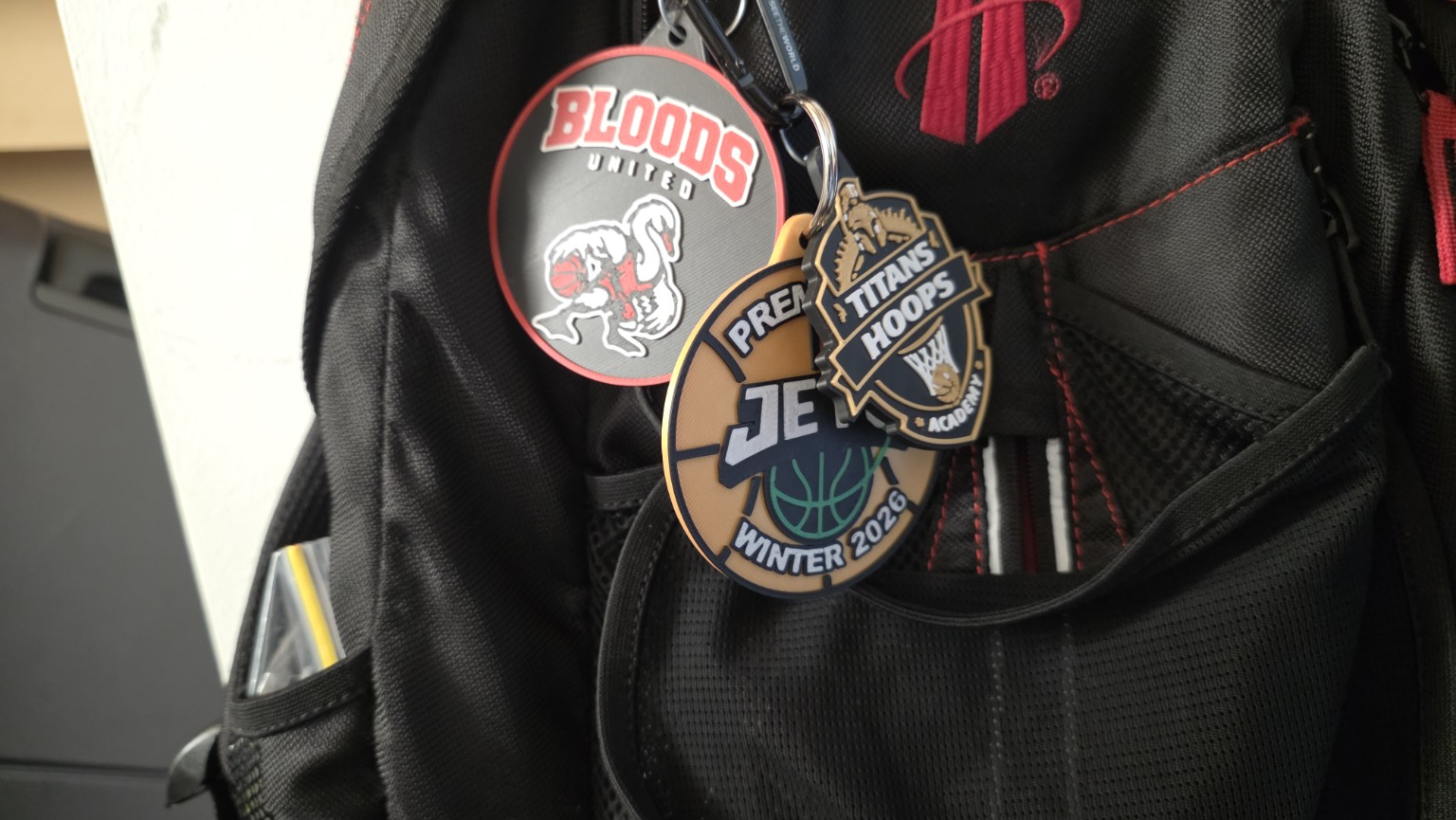 Bloods United, Jets and Titans Hoops keyrings hanging from a black basketball bag.